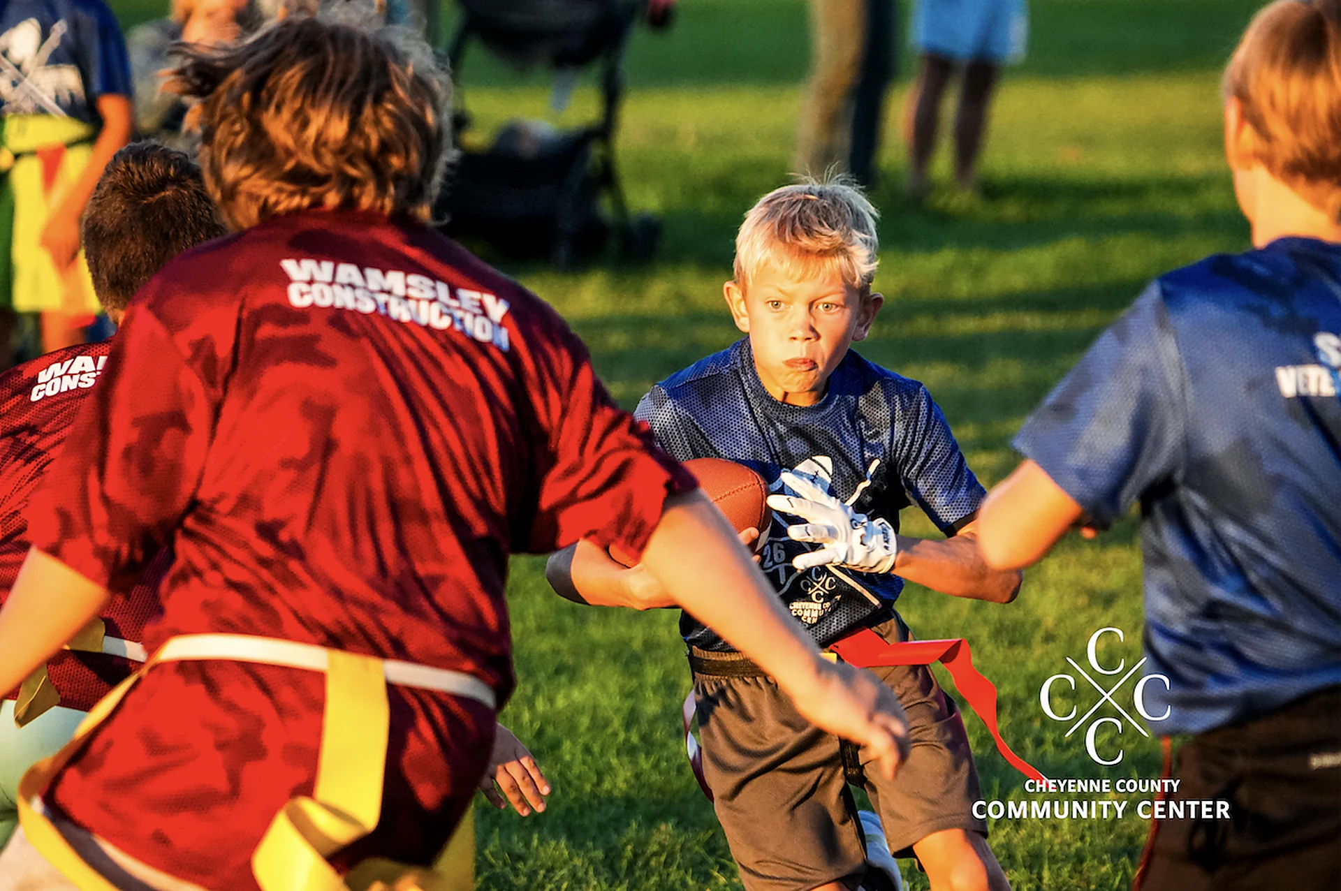 Youth flag football player carrying the ball between defenders during an outdoor game